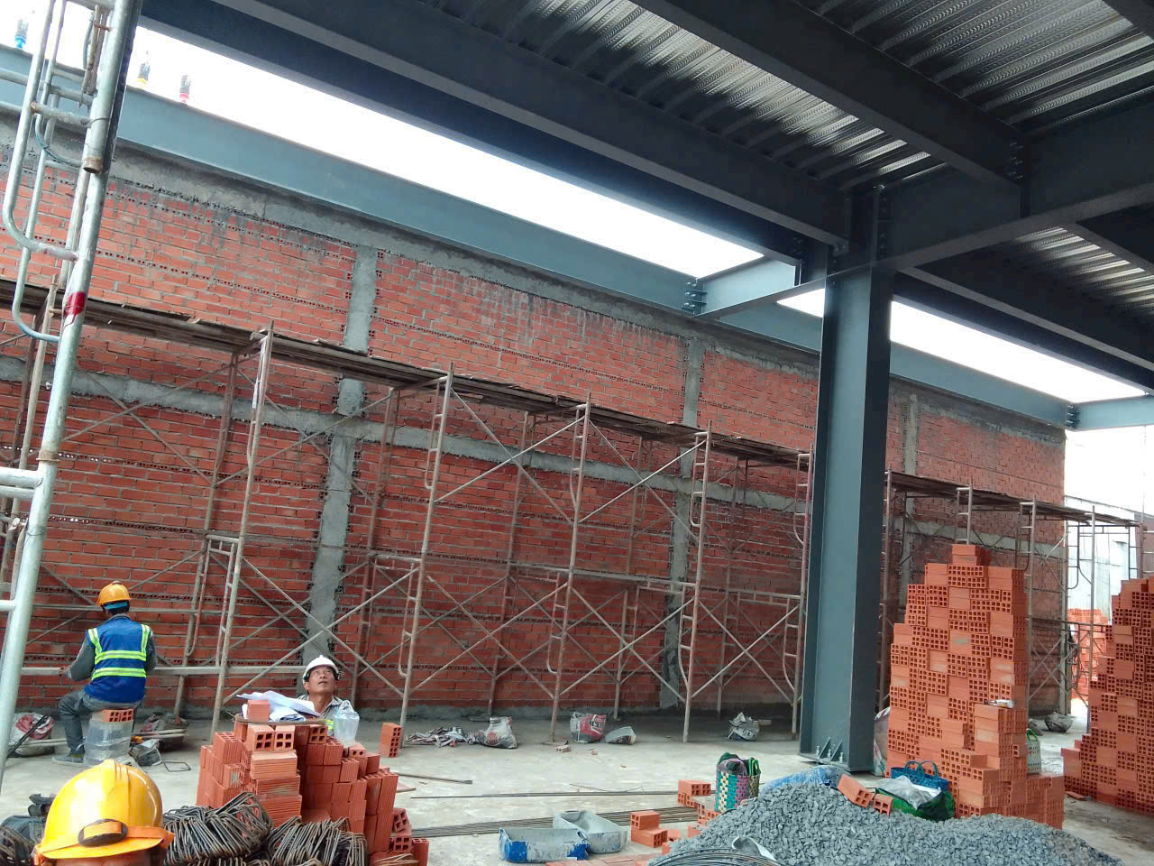 Đội ngũ thợ thi công nhà điều hành Happy One Moir với đồ bảo hộ đầy đủ, đốc thúc xây dựng nhanh.